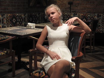 Girl looking away while sitting on chair at restaurant