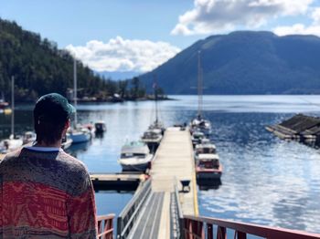 Rear view of man looking at lake against sky