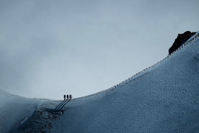 People on snowcapped mountain against sky