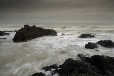 Scenic view of rocks in sea against sky