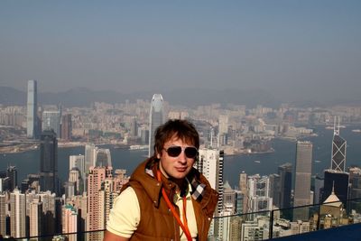 Young man against modern buildings at victoria harbour in city