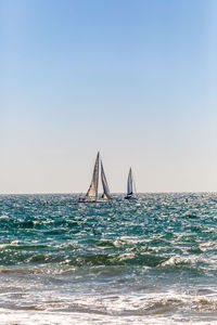 Sailboat sailing in sea against clear sky