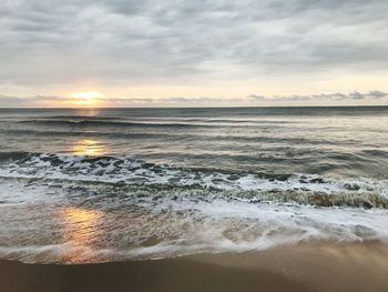 Scenic view of sea against cloudy sky during sunset