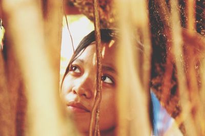 Close-up of thoughtful teenage girl seen through roots