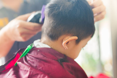 Cropped image of barber cutting boy hair