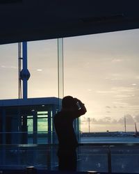 Man photographing through window at sunset