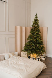 Christmas tree with gifts in the interior of a stylish bedroom