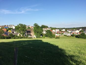 Houses on field against clear blue sky