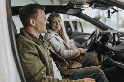 Young couple testing car in car dealership