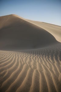 Scenic view of sand dunes against clear sky