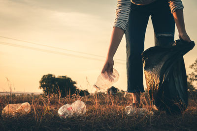 Low section of person standing on field against sky during sunset