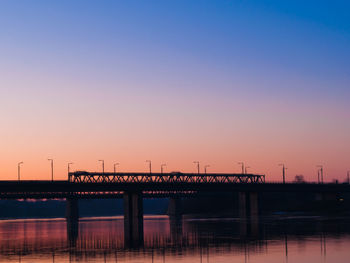 Bridge over river against clear sky during sunset