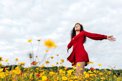 Woman with red umbrella standing on field against sky