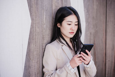 Confident beautiful chinese business woman using mobile phone in city. technology