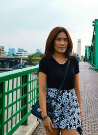 Portrait of woman standing on walkway against sky