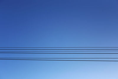 Low angle view of cables against clear blue sky