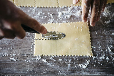 Cropped hands cutting ravioli dough