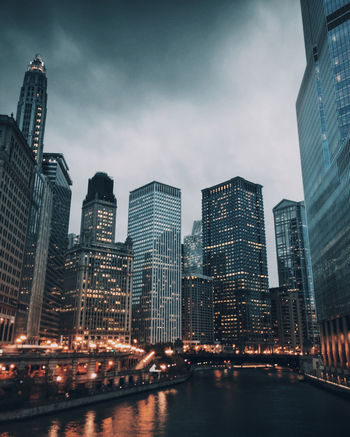 River against illuminated skyscrapers during sunset