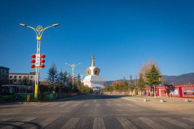 Street amidst buildings against clear blue sky