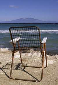 Deck chairs on beach against sky