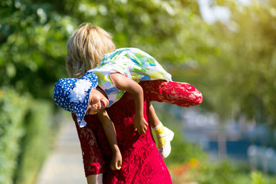 Mother carrying daughter at park on sunny day