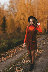 A pretty girl enjoys solitude drinks coffee walks in the autumn forest in nature in fall