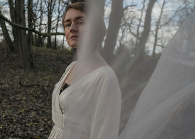 Midsection of woman standing by tree in forest