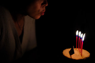 Close-up of young woman blowing birthday cake