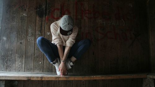 Midsection of person sitting on seat against wall