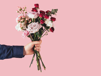 Male hand holding a beautiful bouquet on a pink background.birthday,mother's or valentine's day gift