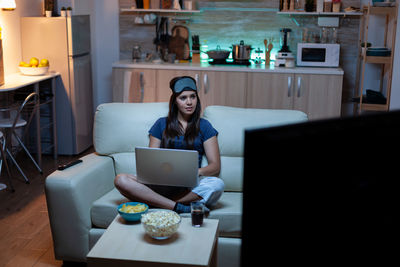 Woman using laptop while sitting on table