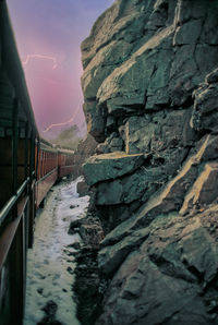 Stone wall by rocks against sky