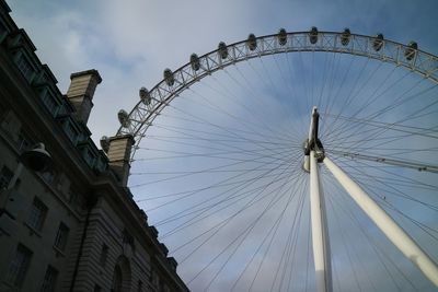 Low angle view of ferris wheel against cloudy sky