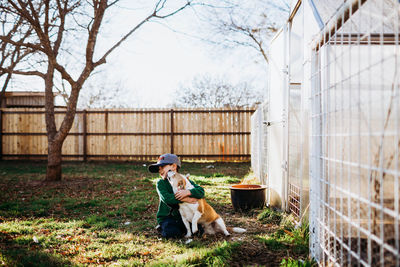 Dog and woman with dogs on fence against plants