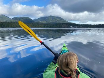 Rear view of girl on lake against sky