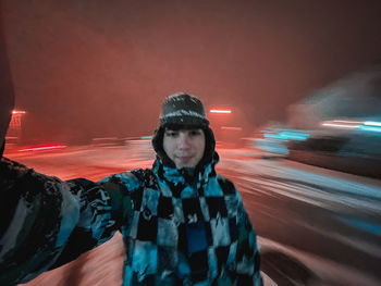 Portrait of woman standing in illuminated city during winter