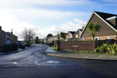 Street amidst houses and buildings against sky