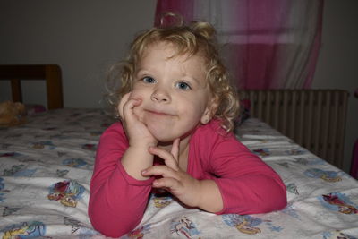 Portrait of cute baby girl on bed at home