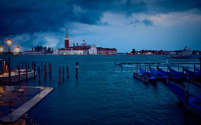 View of buildings at waterfront against cloudy sky