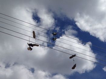 Low angle view of silhouette birds on cable against sky