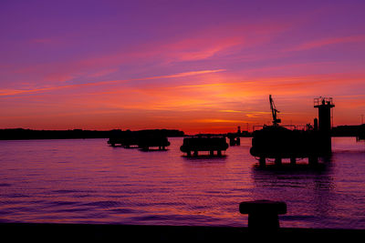 Silhouette boats in sea against romantic sky at sunset