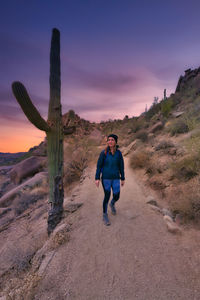 Full length of man standing on land against sky during sunset