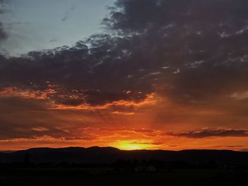 Silhouette landscape against dramatic sky during sunset