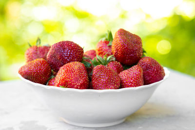 Strawberry in white plate on green background