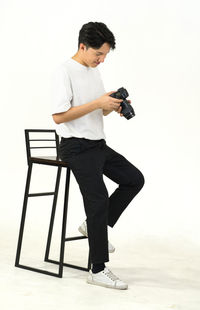 Full length of man photographing against white background