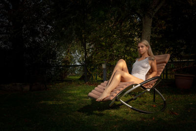 Woman sitting on chair against plants