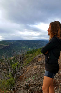 Side view of man standing on mountain against sky