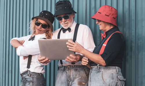 Fashionable family looking at laptop while standing against wall