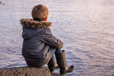 Rear view of woman sitting on shore