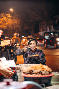 Woman holding ice cream on street at night